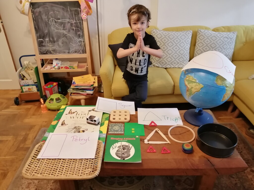 Photo of a child standing next to a collection of household objects of different shapes
