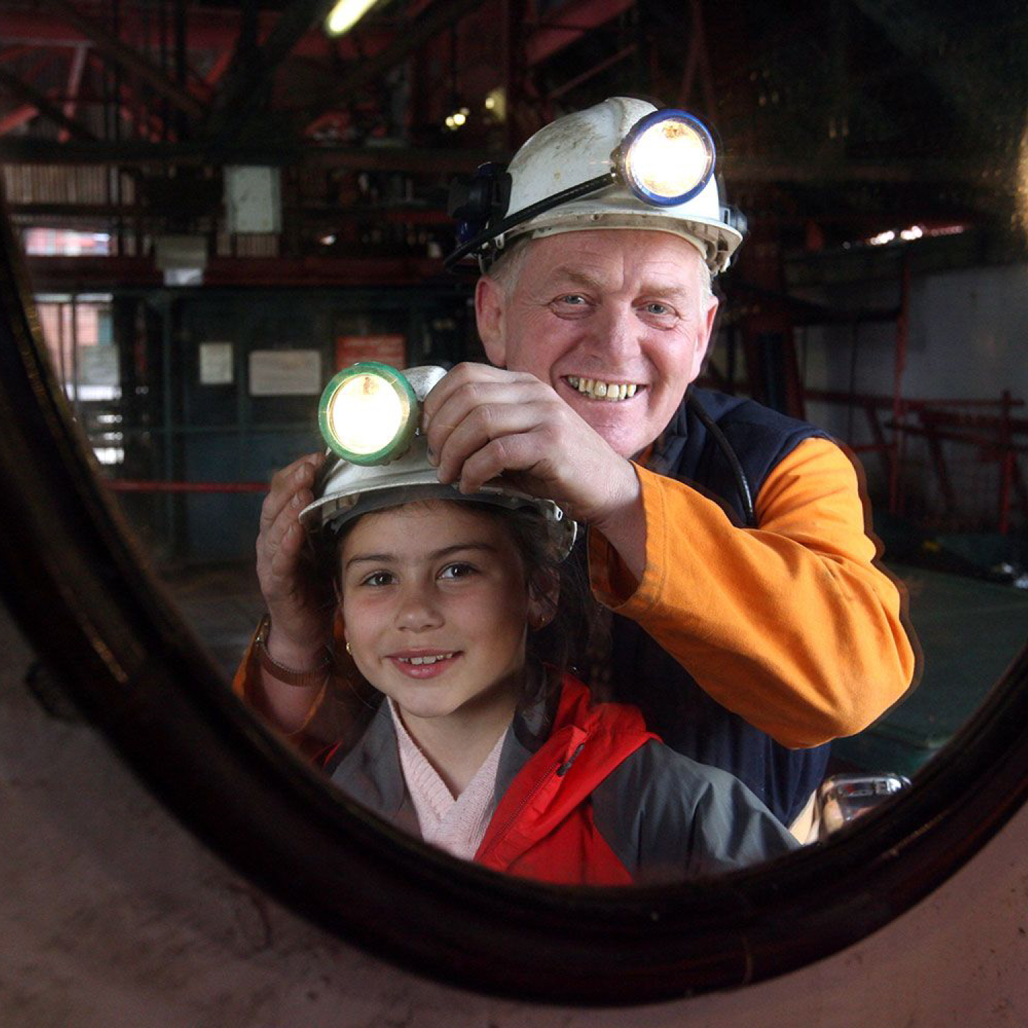 A photo of a miner and a young girl looking in a mirror