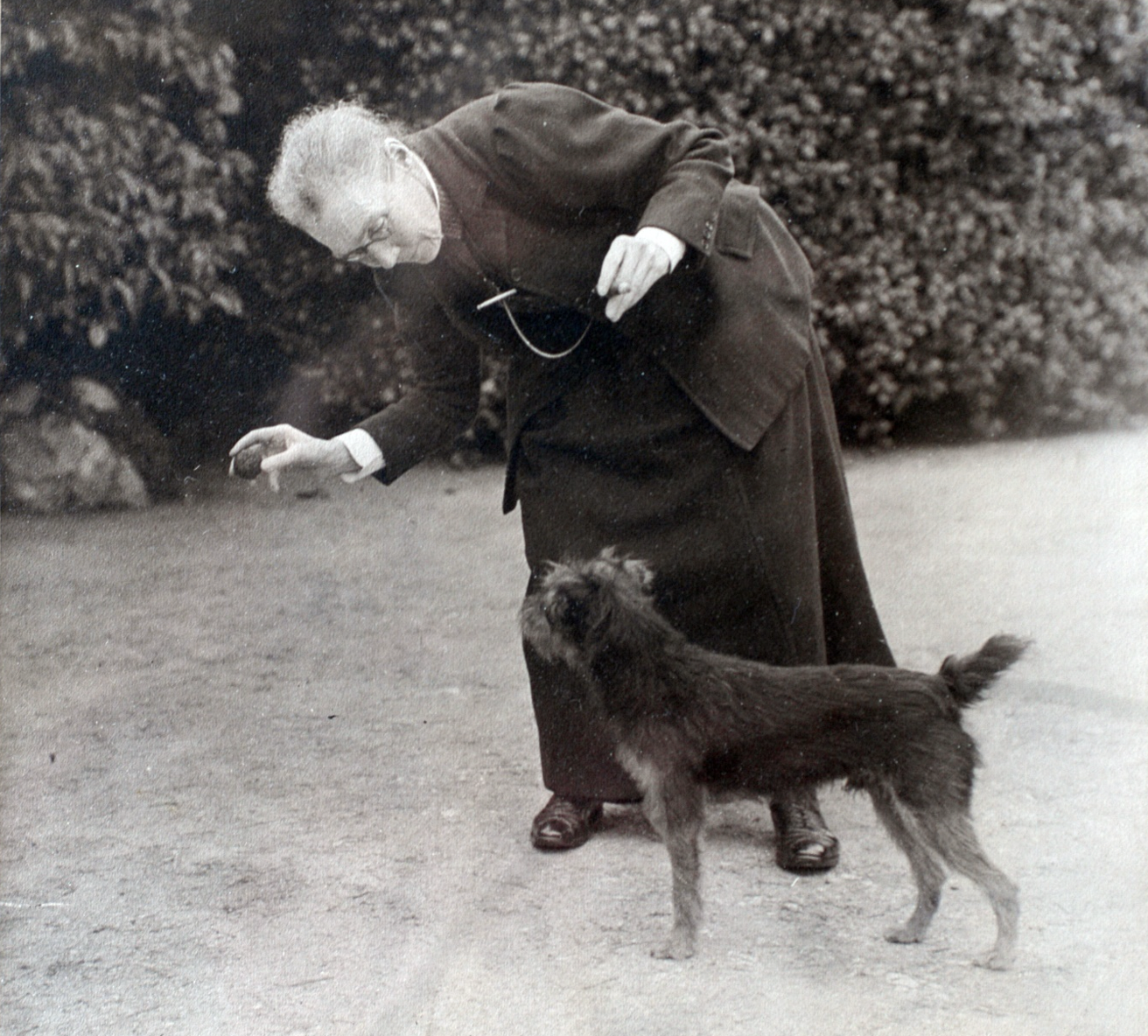 An old photograph of a woman playing with a dog.