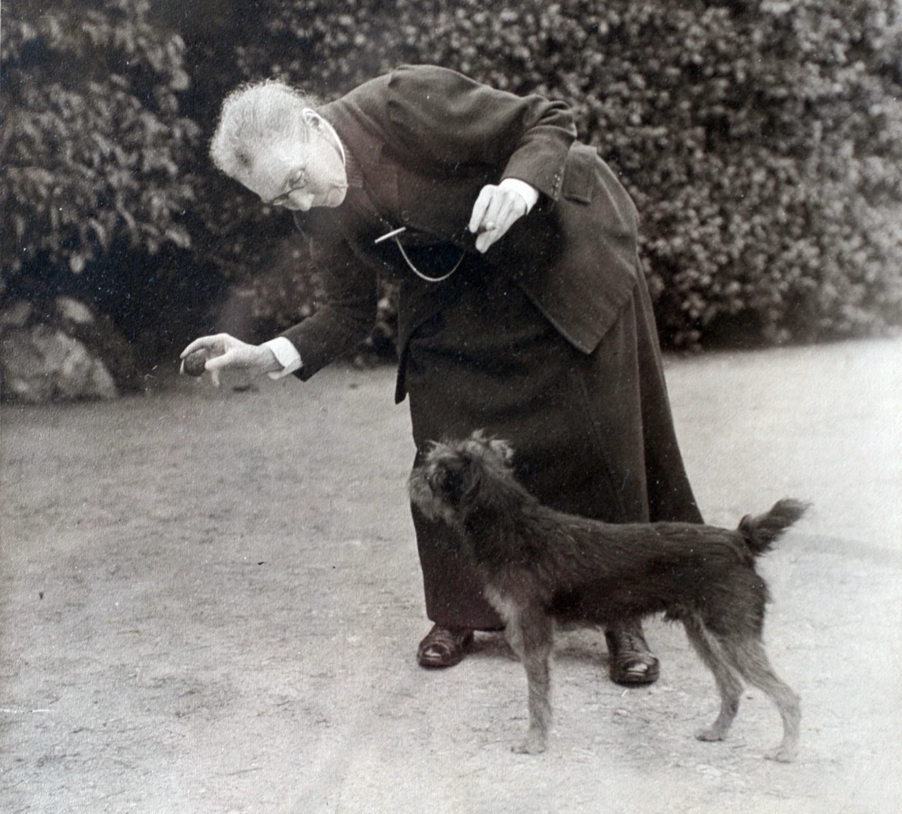 An old photograph of a woman playing with a dog.