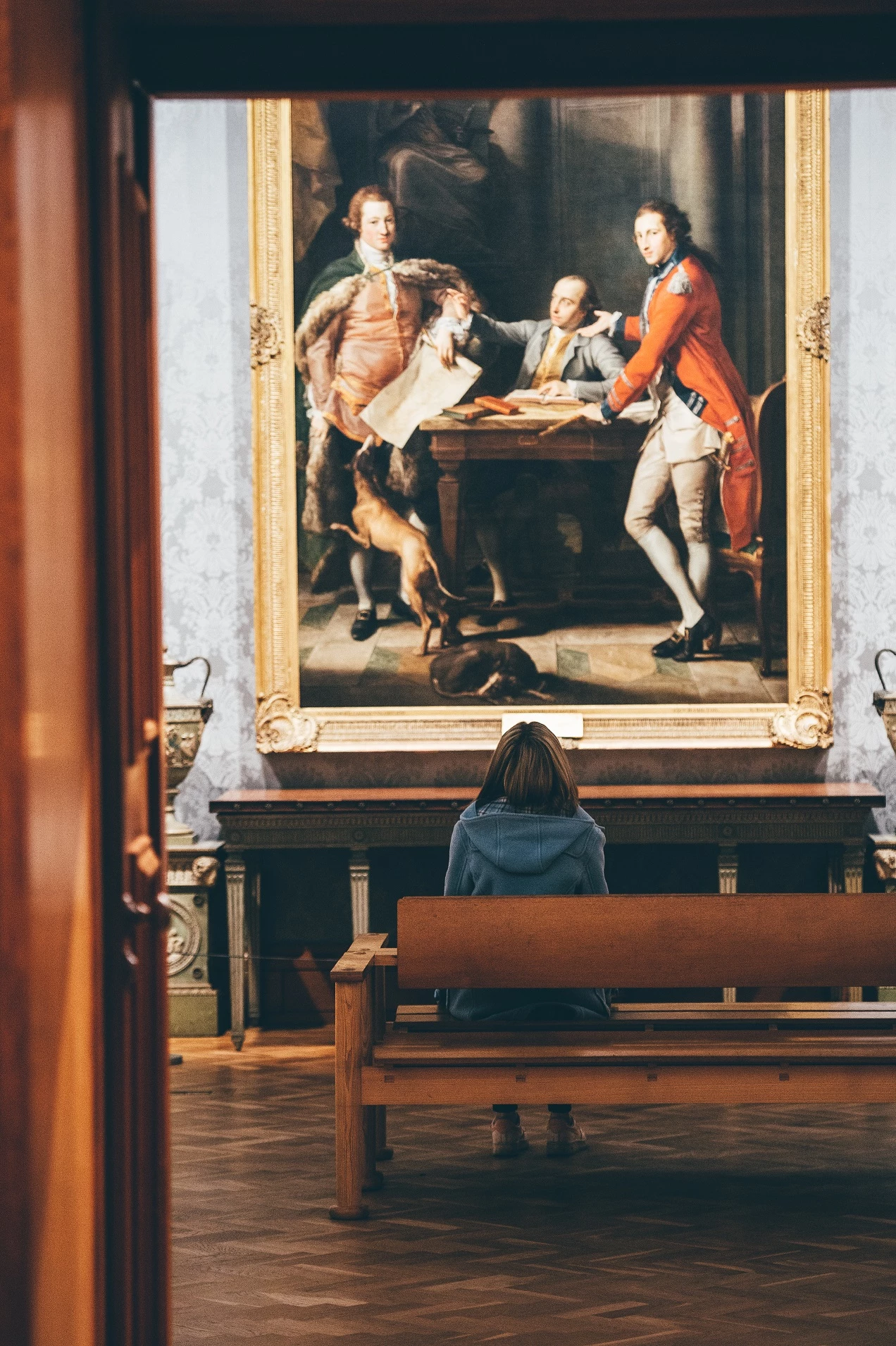 A woman sits in front of an historic painting