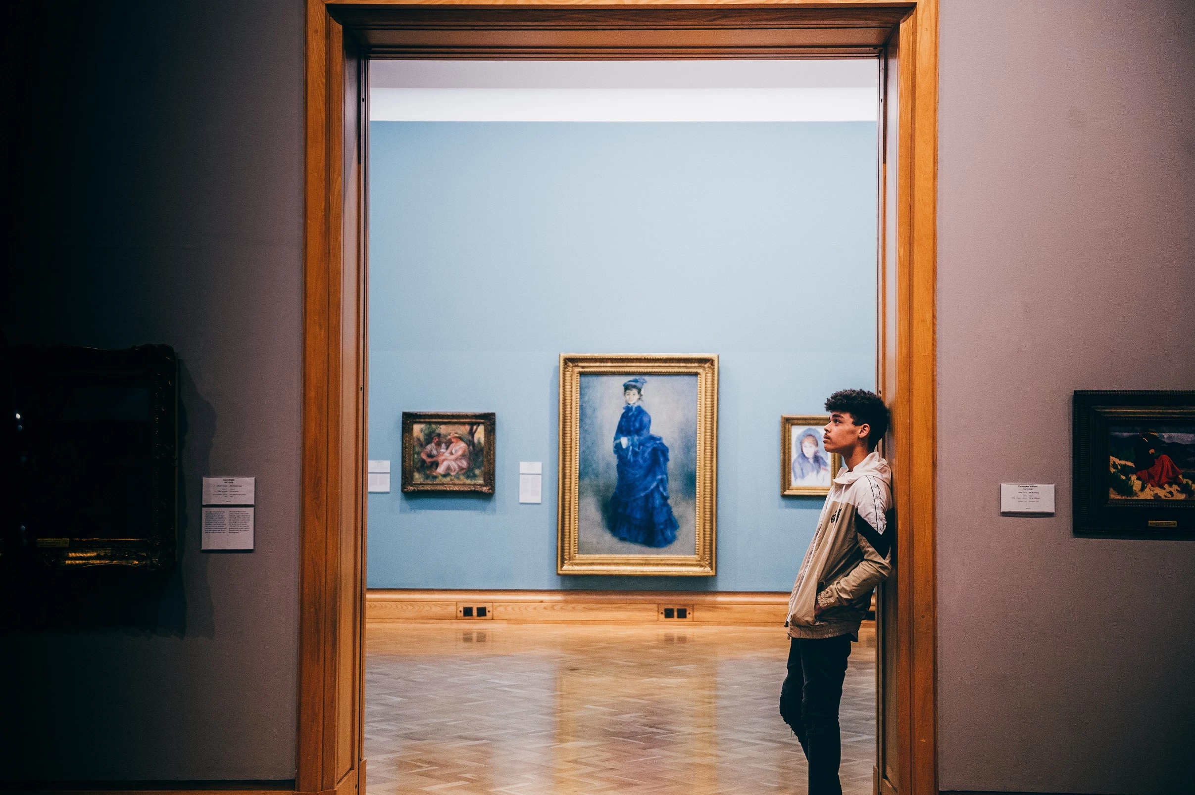 A young man stands in the gallery in front of Renoir's La Parisienne