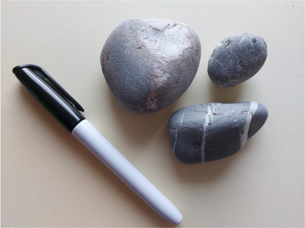 Photo of three small pebbles and a black permanent marker