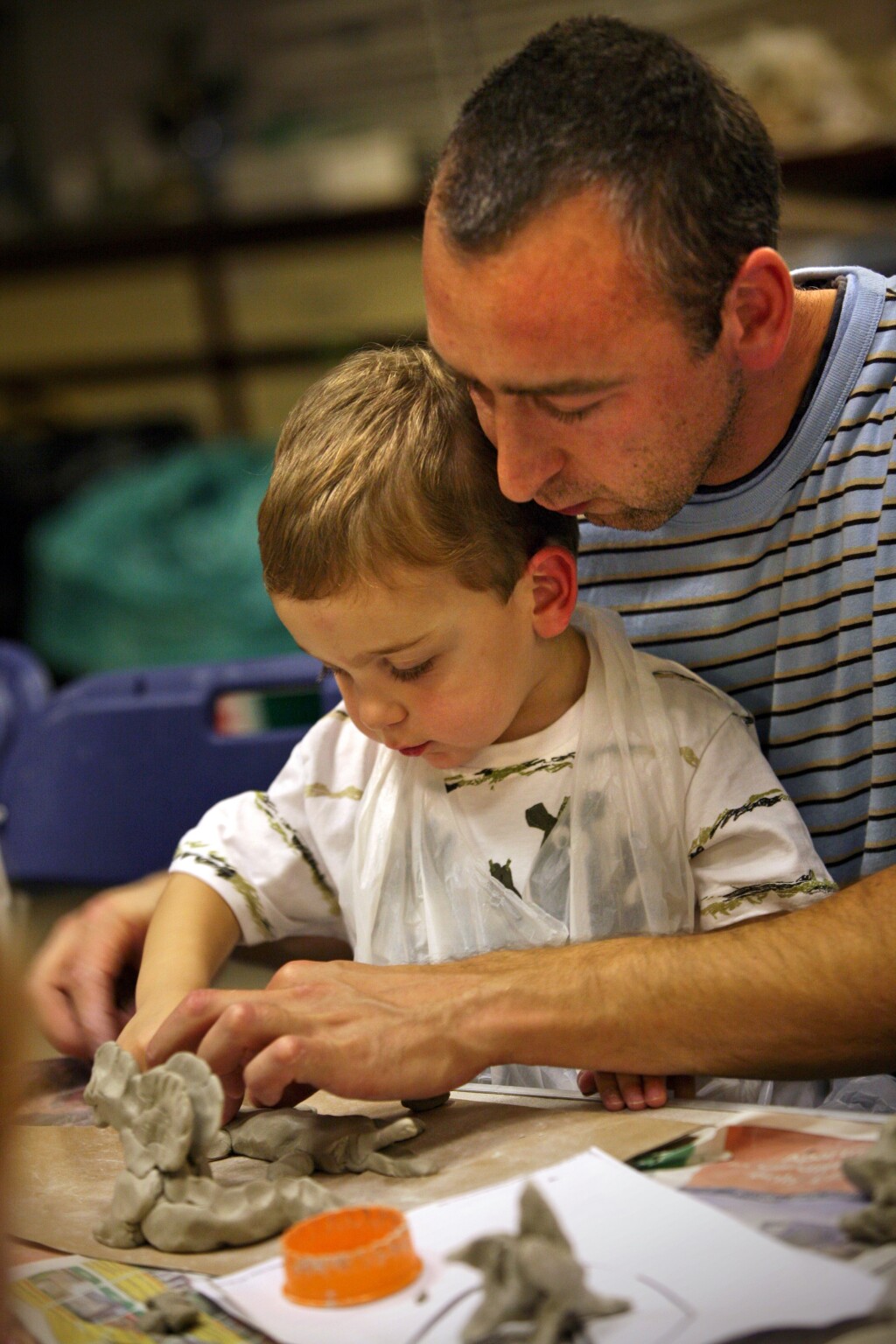 A young child and an adult make clay sculptures by hand
