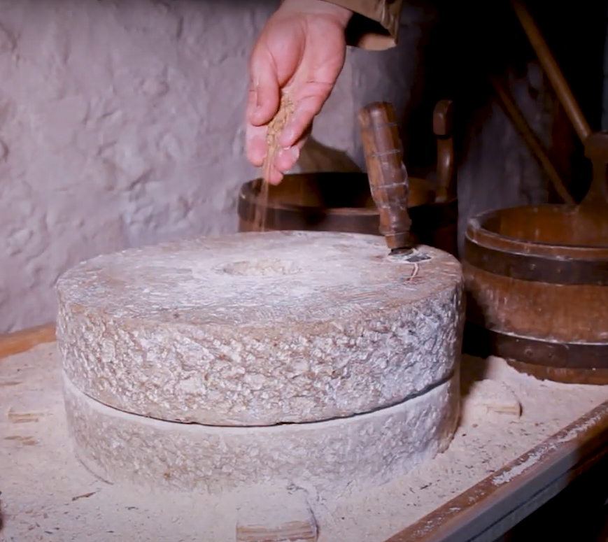 Grain is poured by hand into a millstone