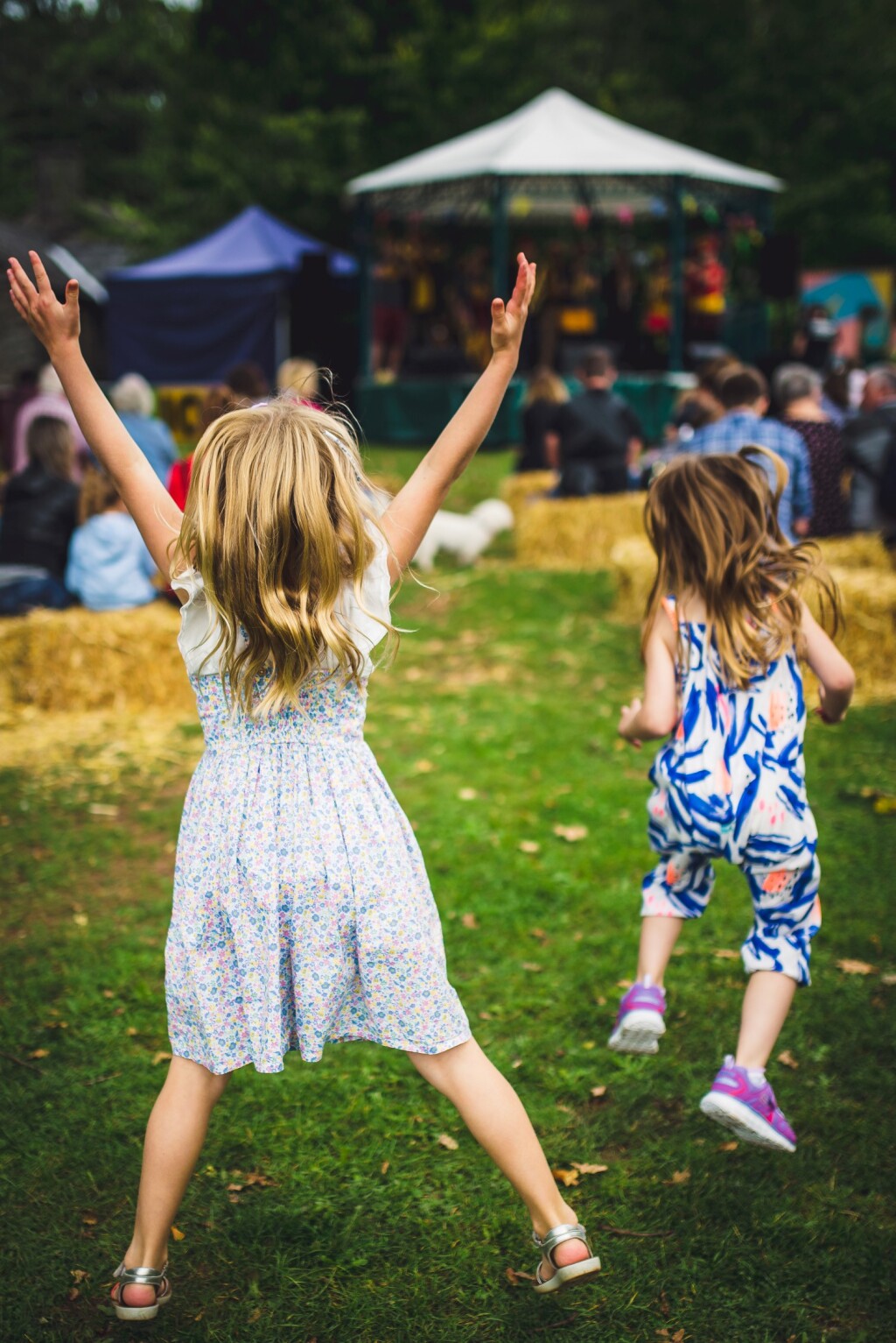 Two young girls jumping in front of the band stand on Gwalia Green 