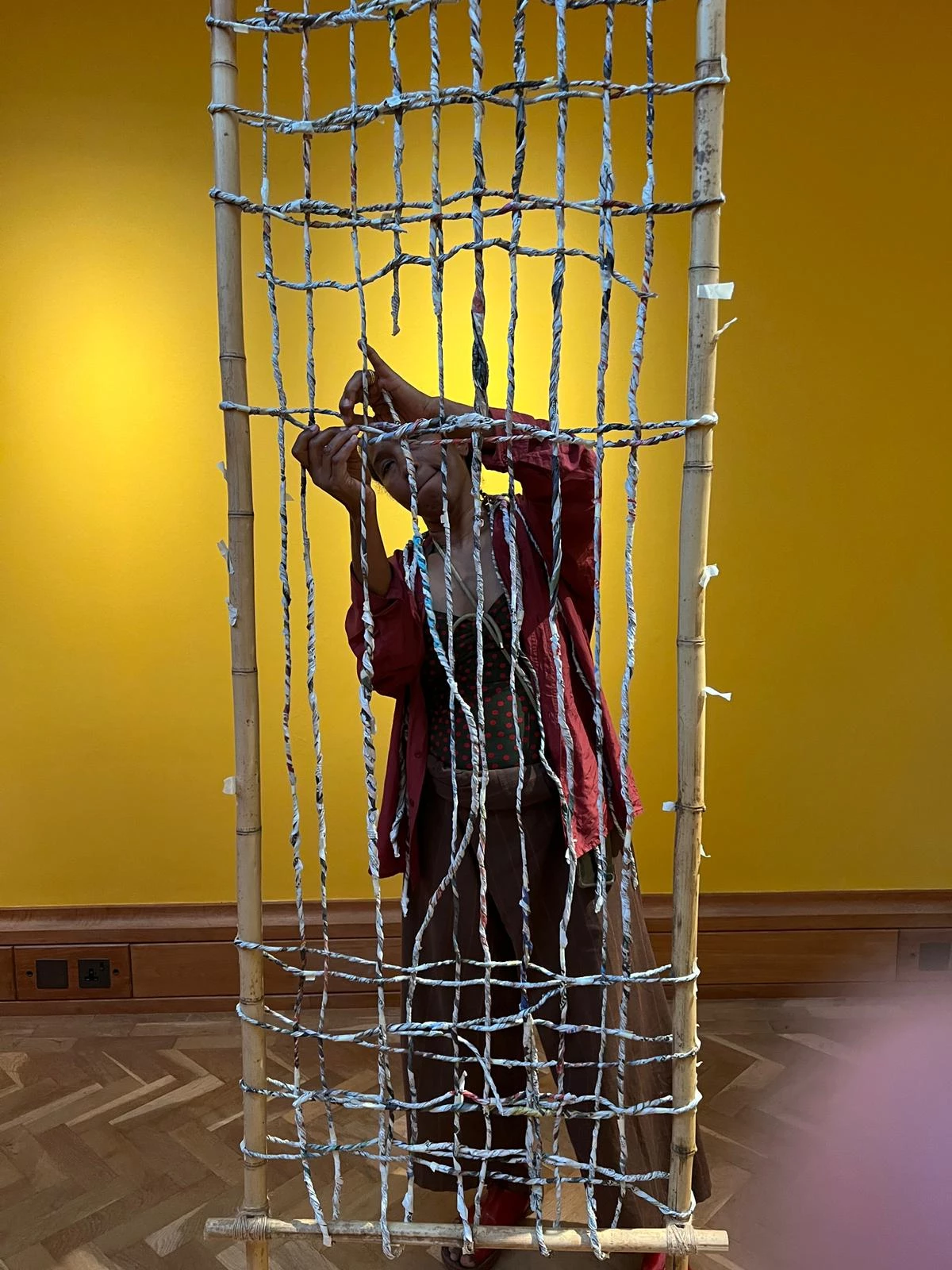 A woman weaves twisted paper in an art gallery