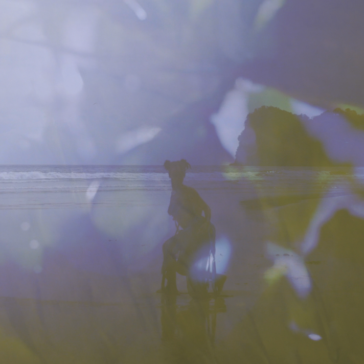 A still from Gesiye's film, showing a woman dancing on a beach. The photograph has a blue filter over it