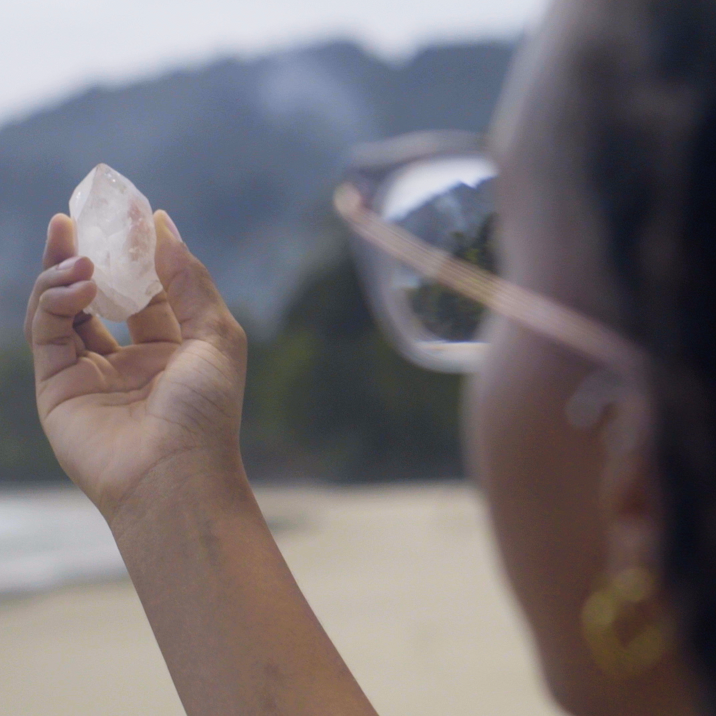 A still from Gesiye's film, showing a woman holding up a crystal so the light shines through it.