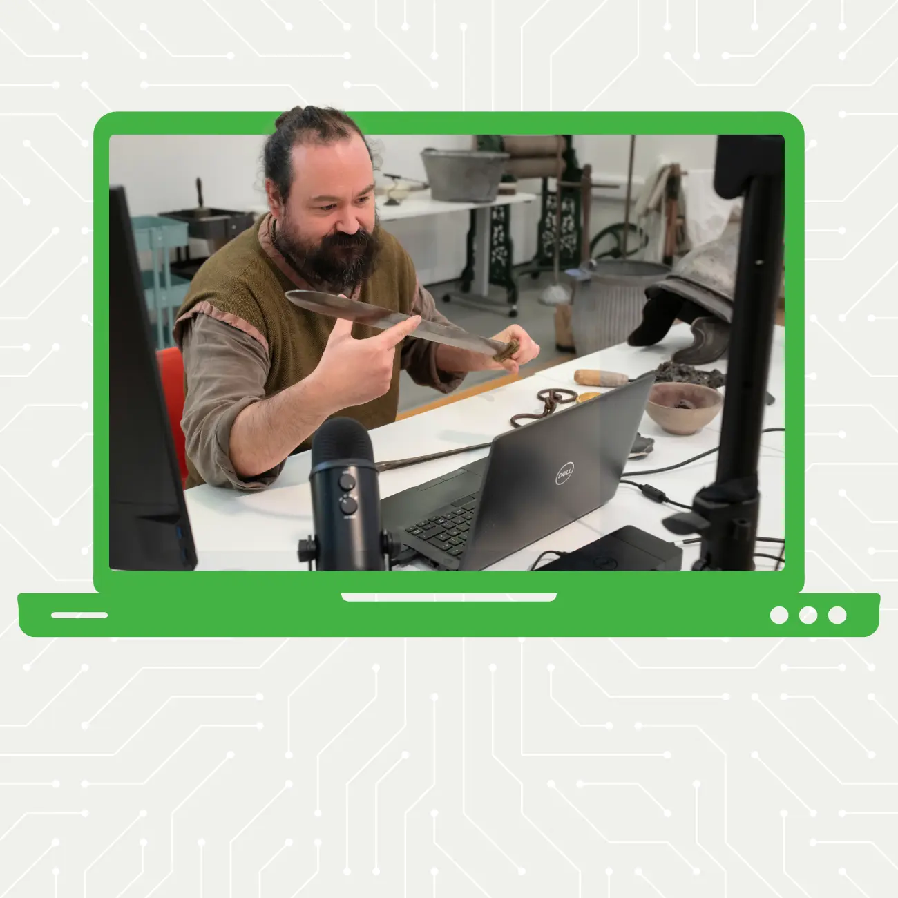Man in green Celt tunic holding a sword in front of a camera