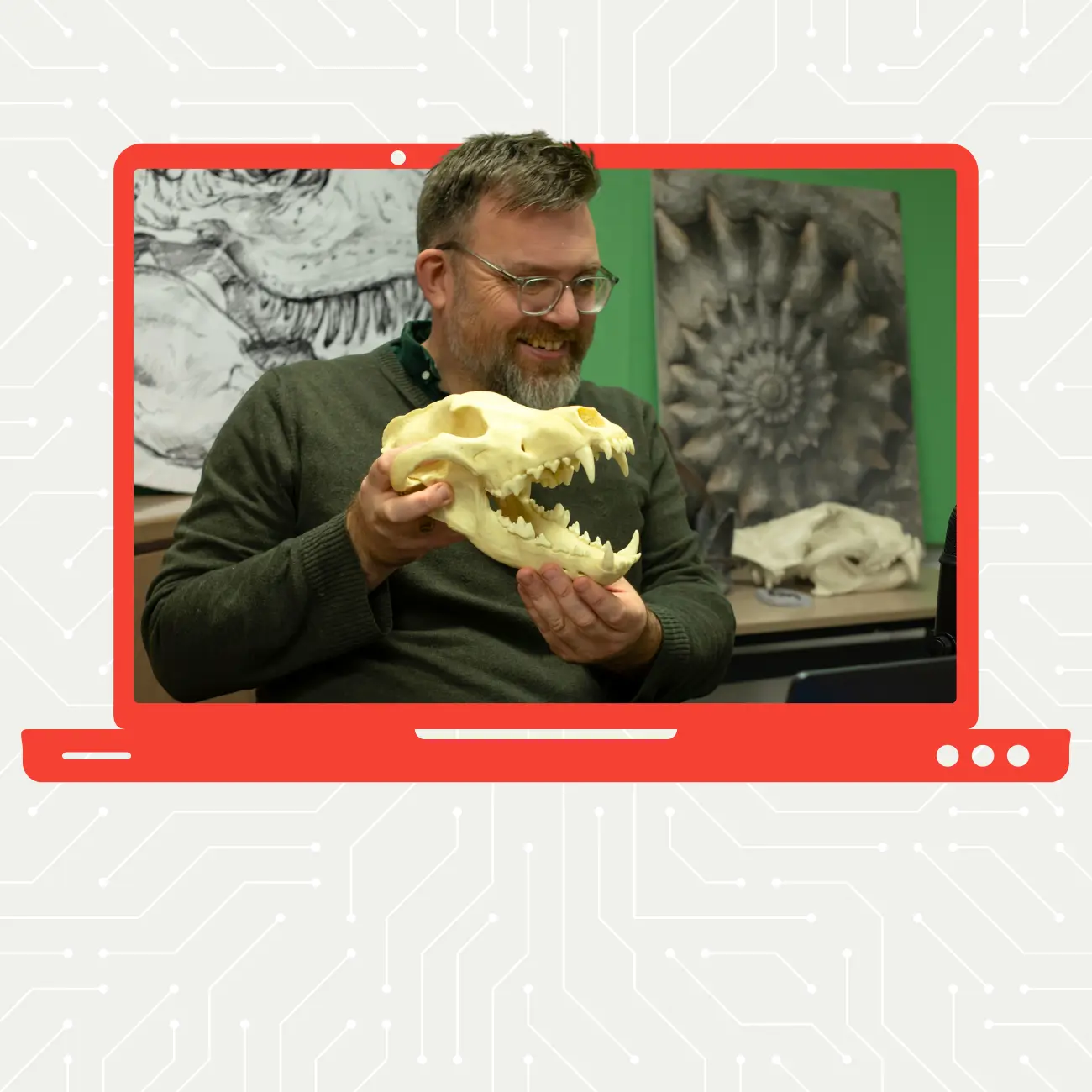 Man in glasses holding a dinosaur skull up to a camera