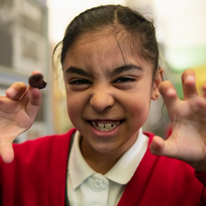 Photo of a young child holding a fossil claw and snarling like a dinosaur