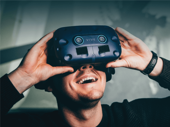 a young man in a rumble seat wearing a VR headset and with his arms outstretched 