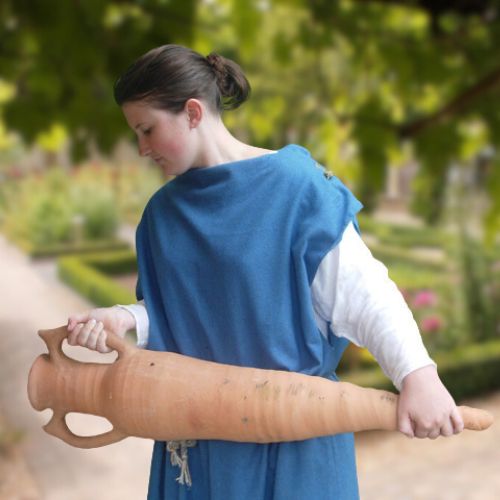 Woman in Roman costume stood in a garden setting.