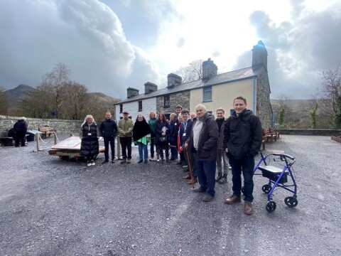 A group of people standing outside a row of re-erected cottages