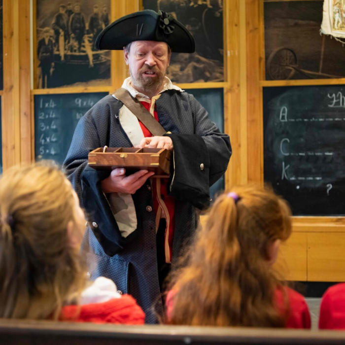Man dressed as a pirate showing children a treasure box.