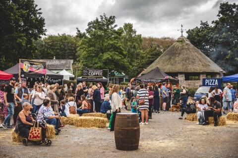 A group of people sat on hay bails surrounded by food trader stalls