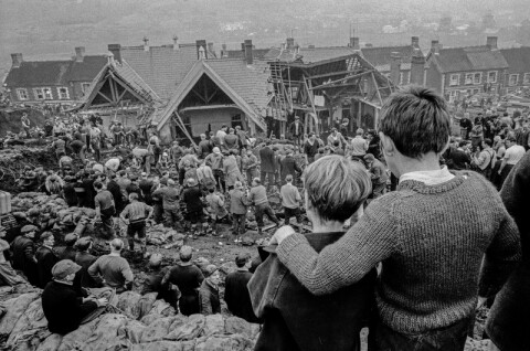 Aberfan Coal Slip Disaster. Two surviving children stand at the top of the hill overlooking the miners digging to find children still buried in the slag.