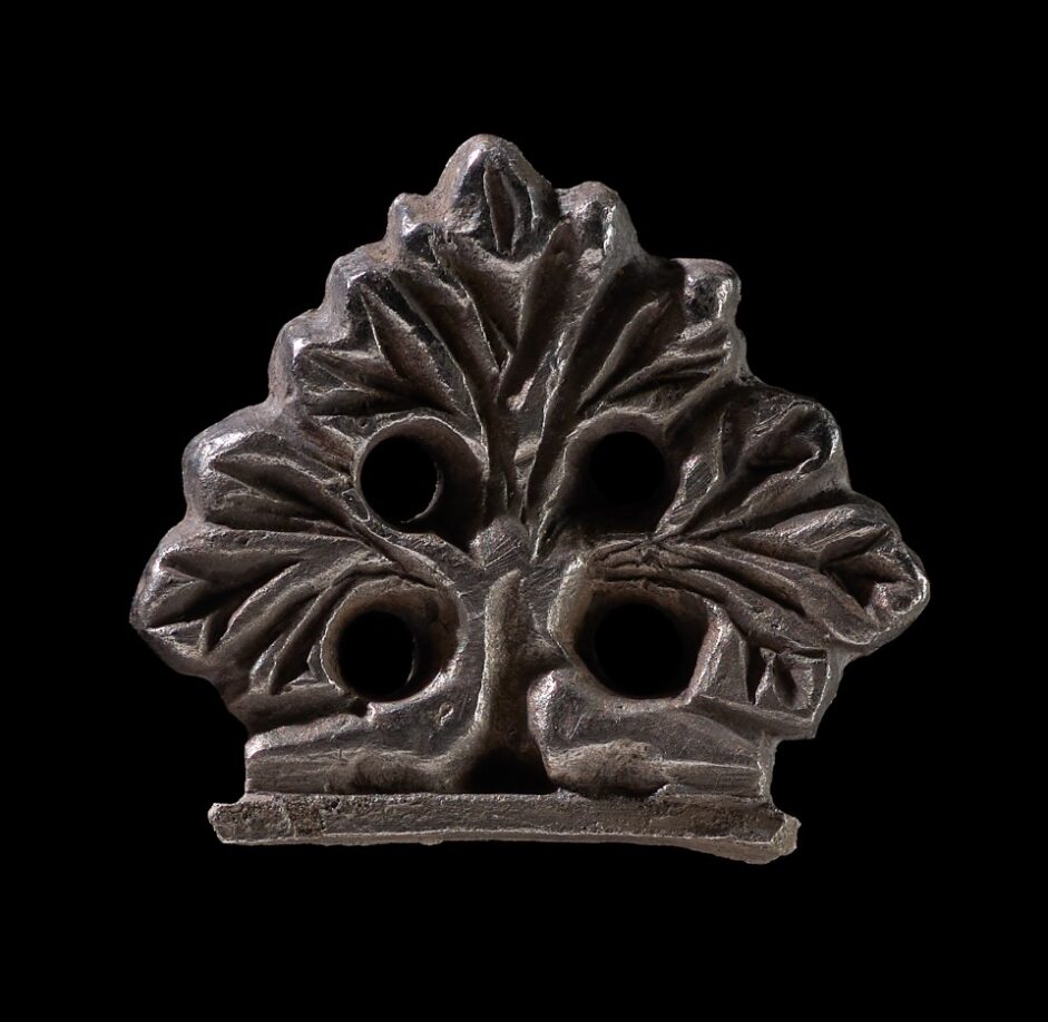 A medieval silver terminal fragment with an openwork plant and leaves design