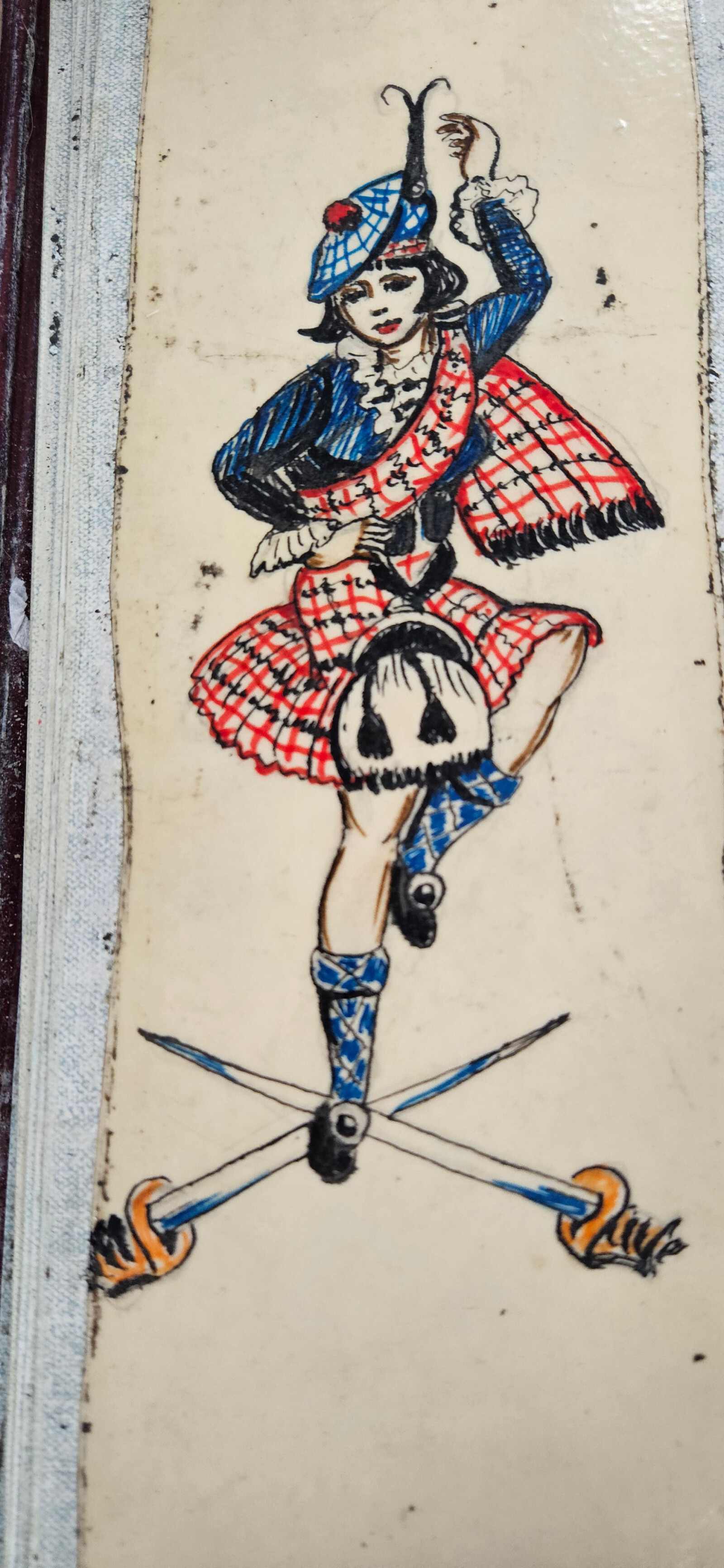 A design of a woman in a kilt dancing above two swords which are crossed