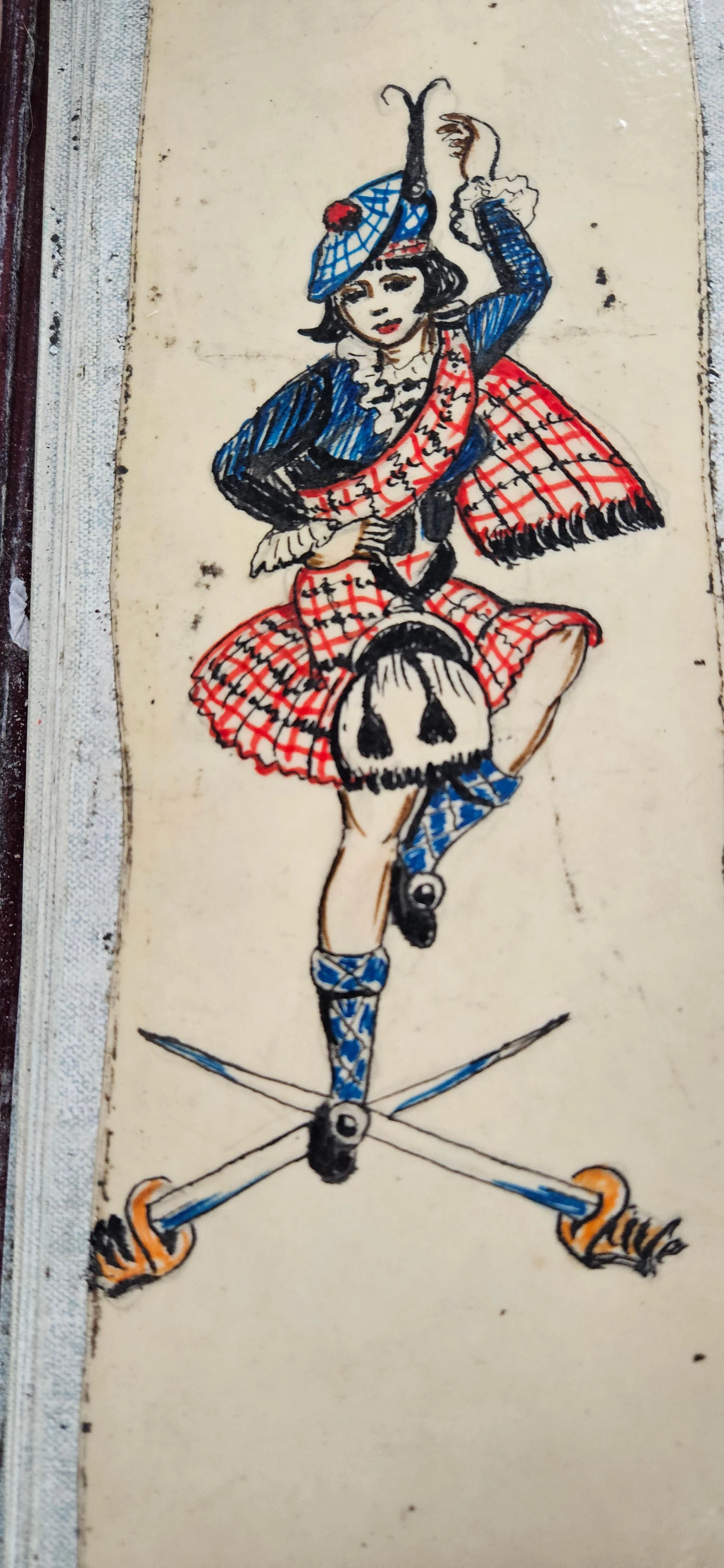 A design of a woman in a kilt dancing above two swords which are crossed