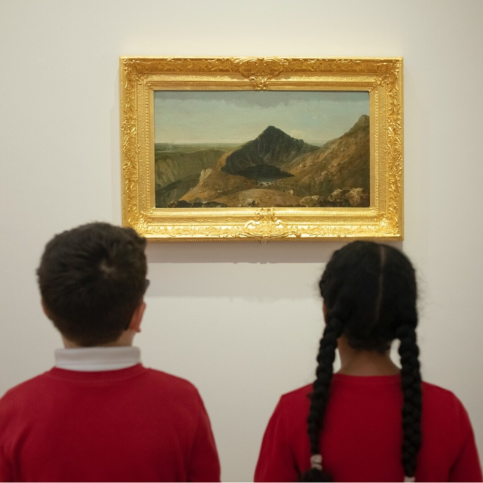 A photo of two children looking at a landscape painting