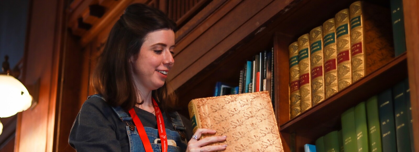 A student work placement lifting a book off a shelf in the museum library.