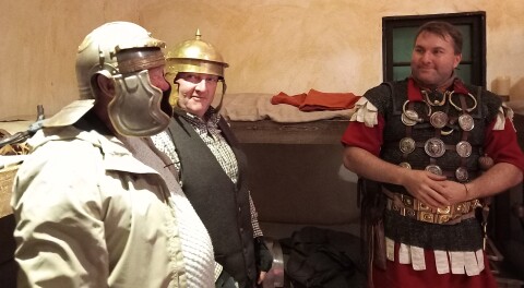 Man dressed as a Roman soldier talking to two visitors