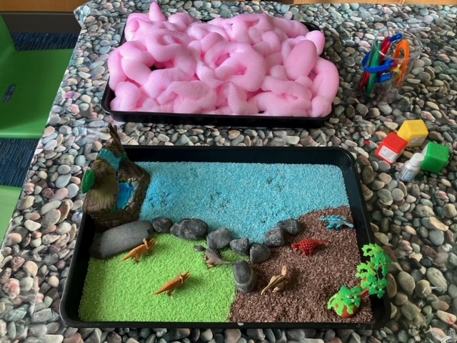 Photo of sensory dinosaur play materials, including toys and bright pink foam