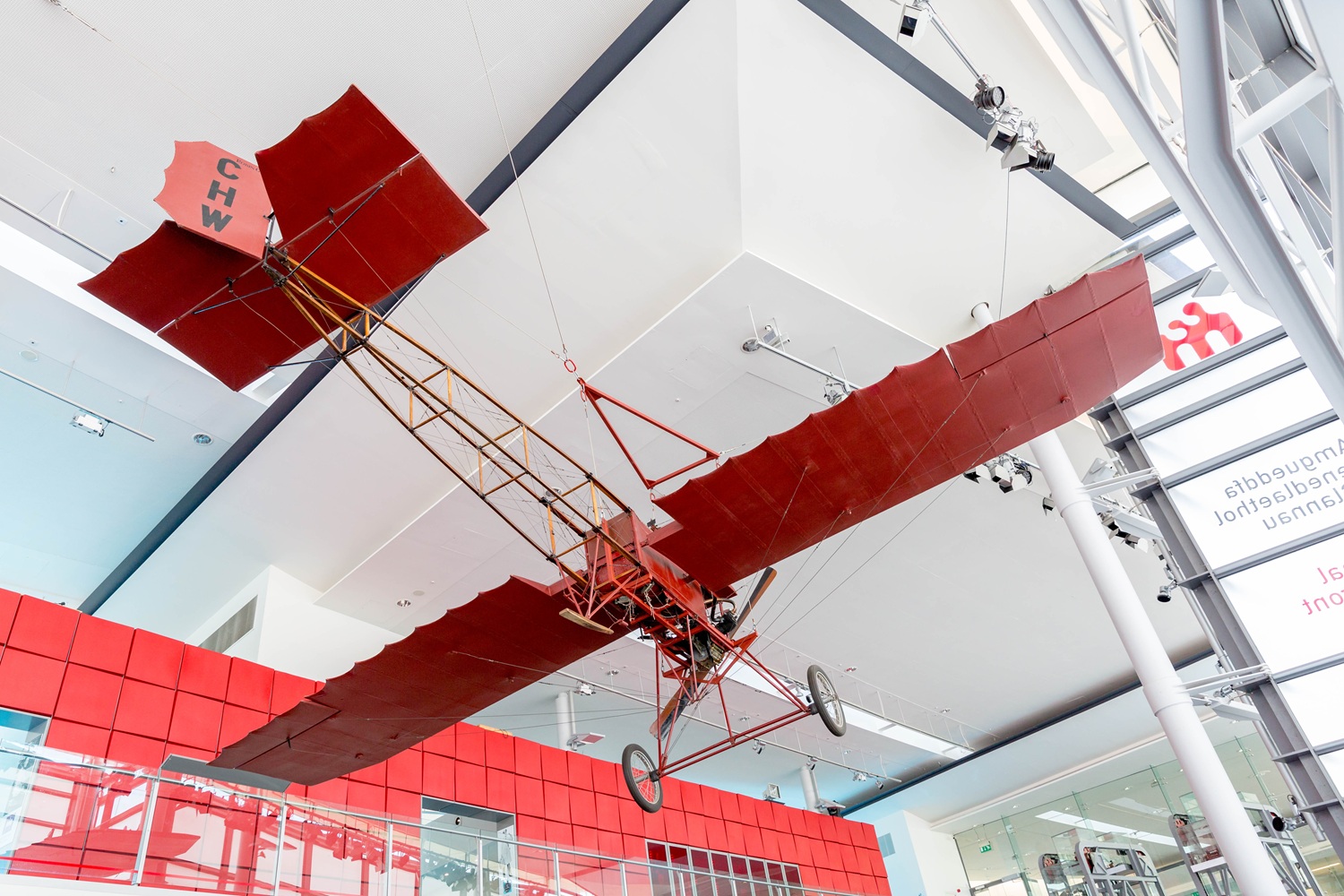 The robin goch aircraft is hanging from the ceiling at National Waterfront Museum, it a red light aircraft with the letters CHW viewed clearly on the back