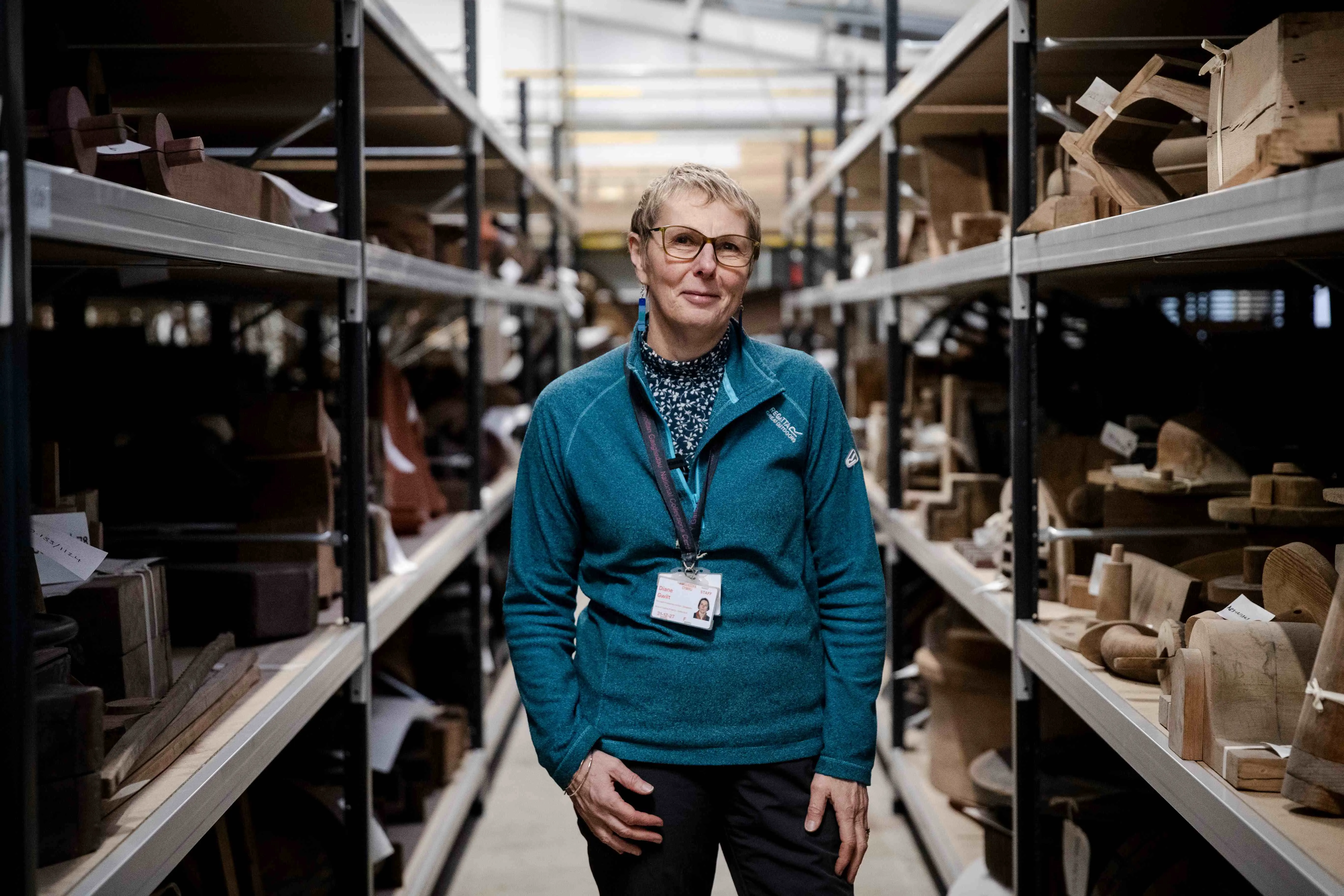 A woman standing in hte middel of two aisles of wooden pattern collections