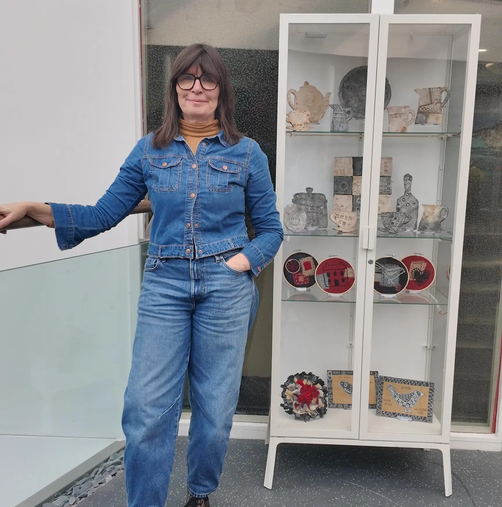 Artist, Rachel Evans, next to a display of creative works made during workshops in Alltwen hospital.