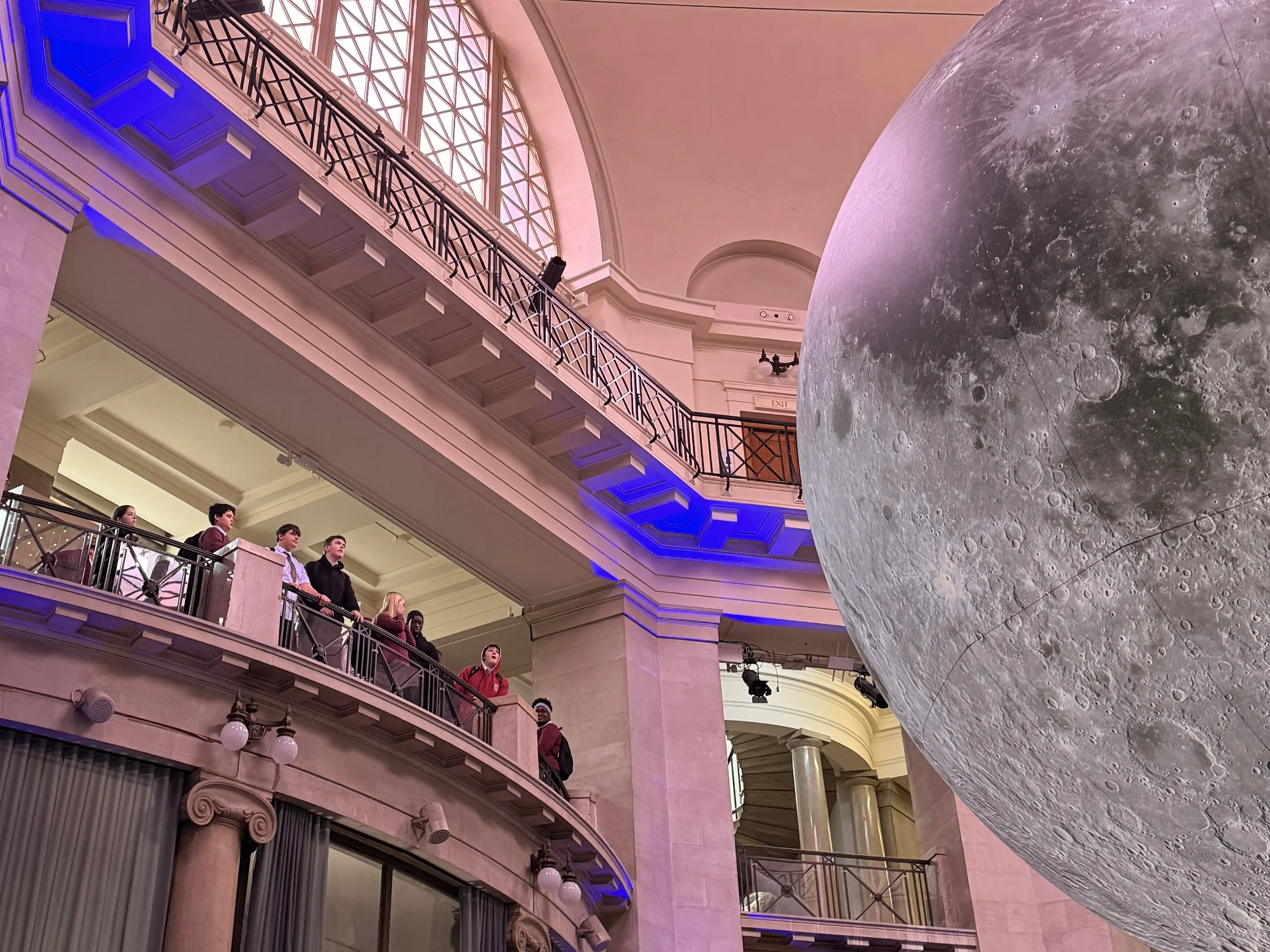Pupils from Cardiff West Community High School viewing the Museum of the Moon sculpture from the balcony
