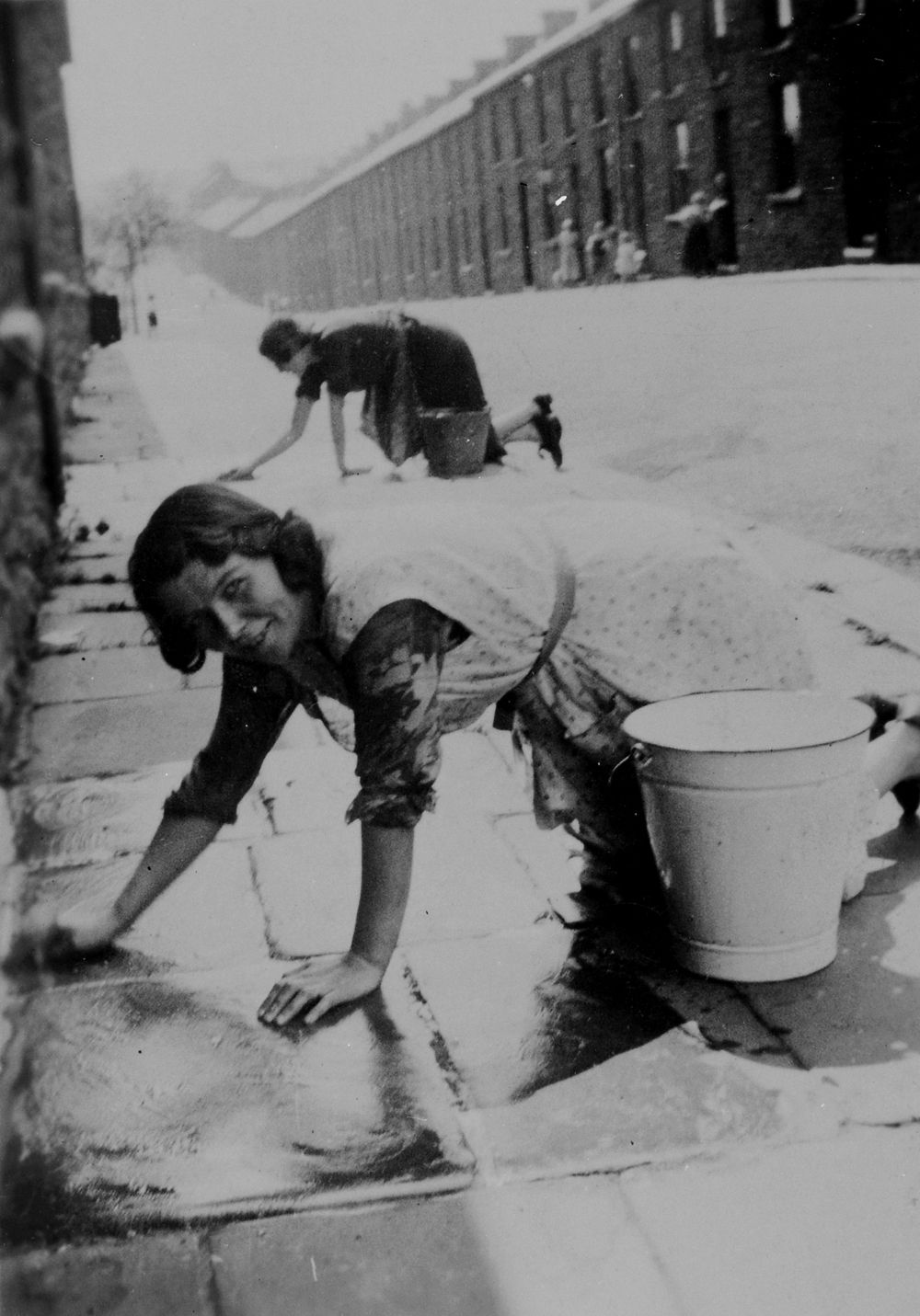 Washing the pavement outside the front door, 1930s.