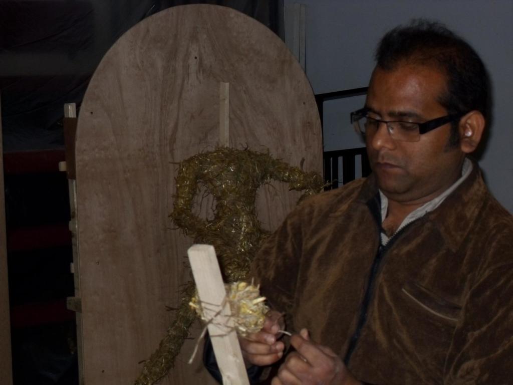 The artist Dibyendu Dey weaving wire and hay to form a head