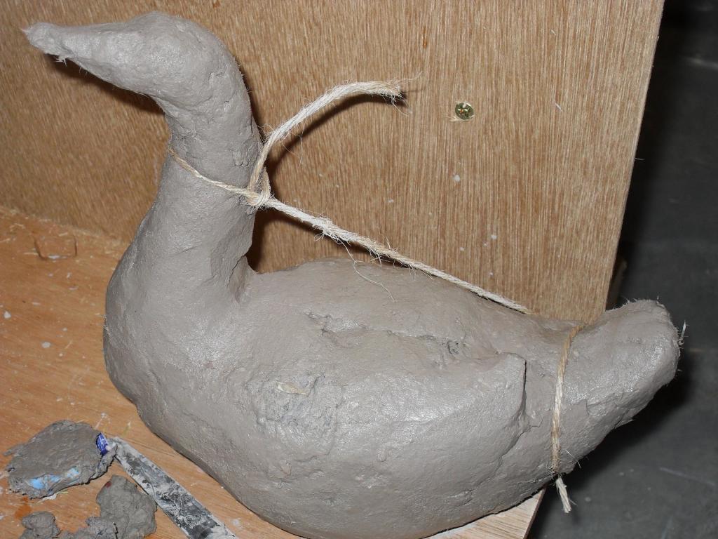 Securing the neck of Sarasvati's swan to the body with string as the clay dries