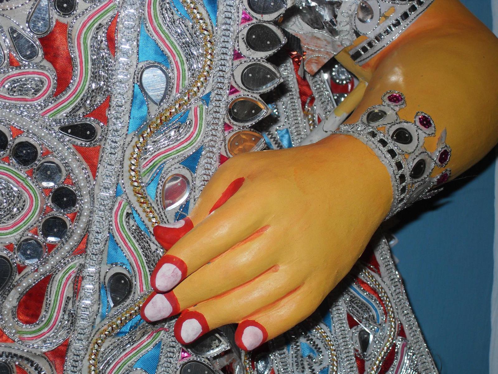 A close-up of Lakshmi's hand and costume